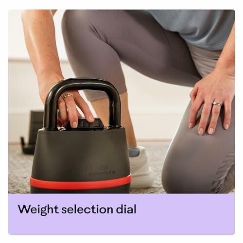 Person adjusting weight on a kettlebell with selection dial.