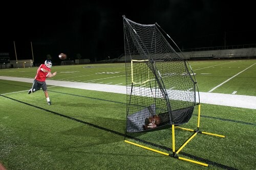 Football player practicing with a net on a field.