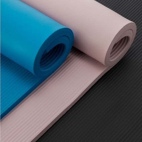 Rolled blue and pink yoga mats on a black surface.